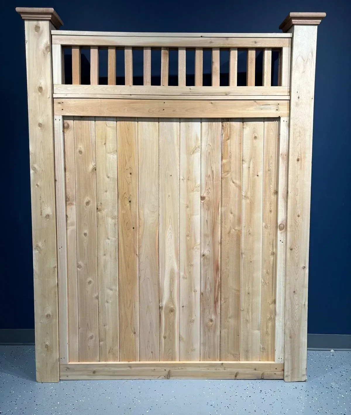 Wooden gate with vertical planks, topped with a slatted section and decorative posts.