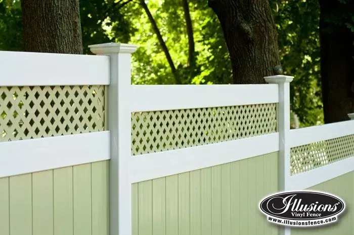 White and light green vinyl fence with lattice top, in a wooded setting.